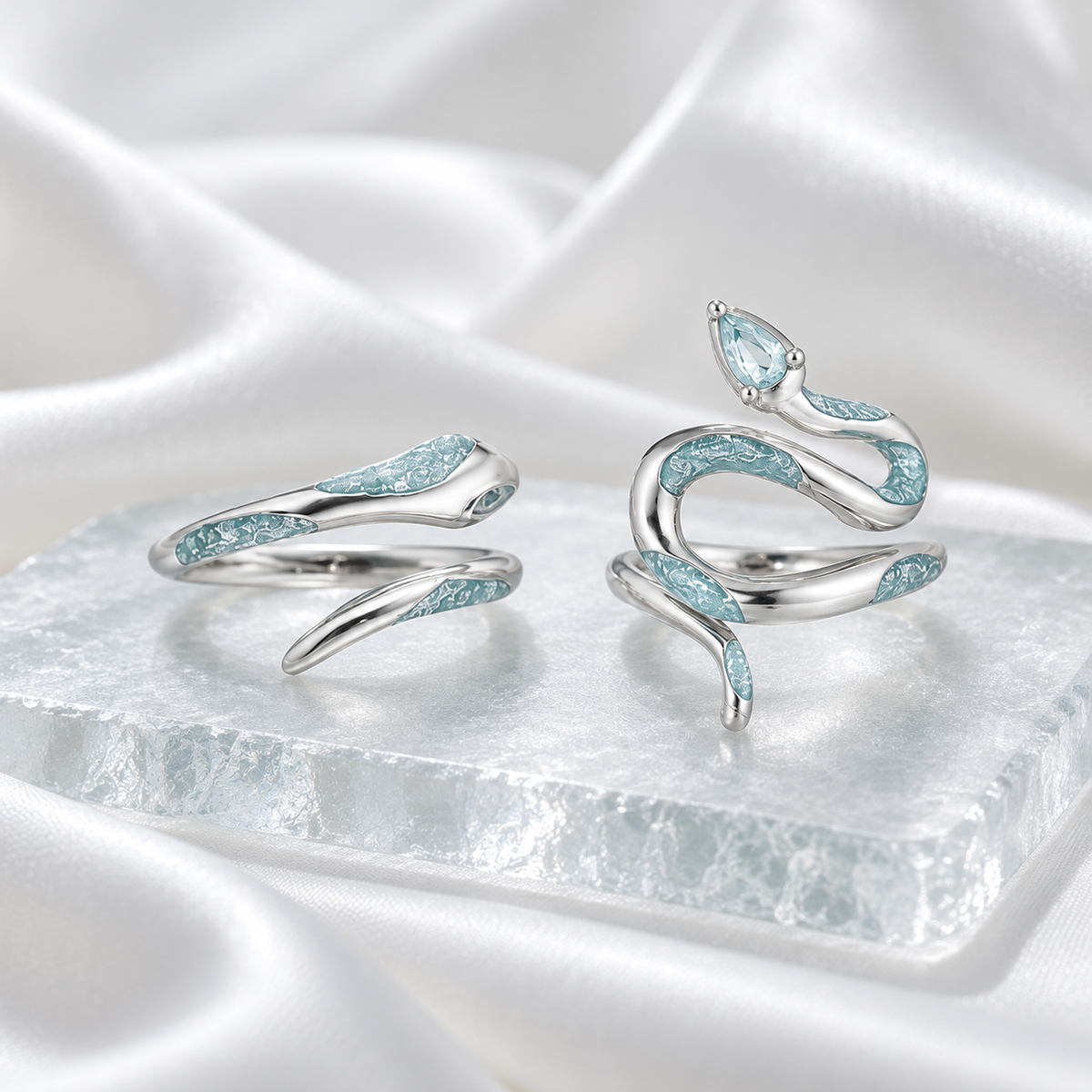 Two pale blue snake rings on frosted glass and white satin