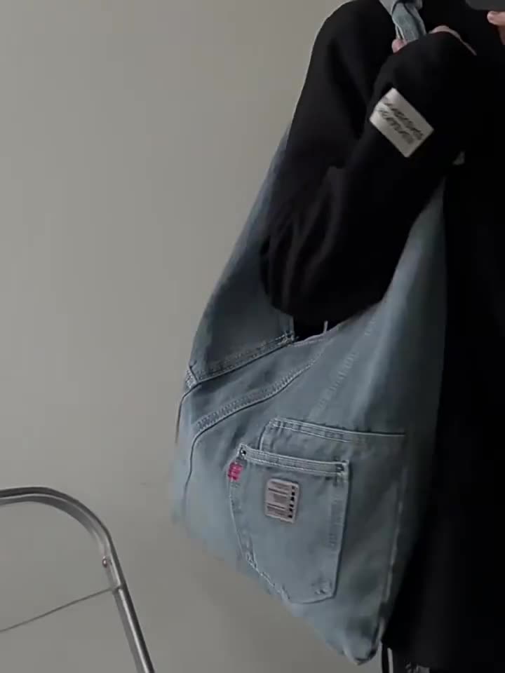 Light blue denim triangle bag worn on the shoulder