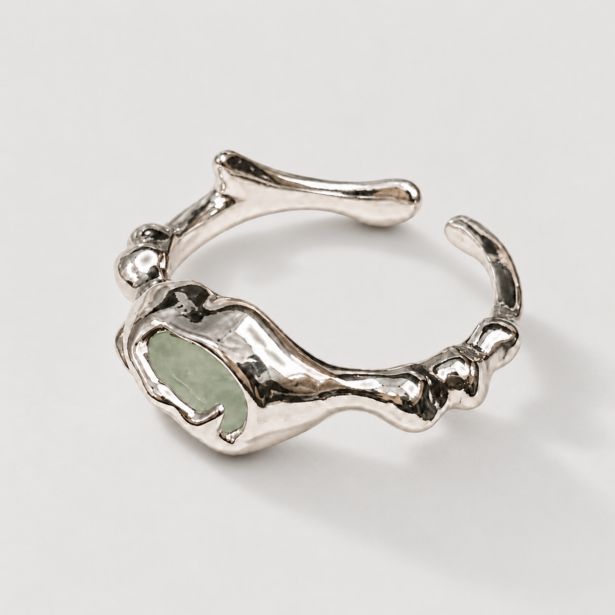 Organic silver-tone open ring with pale stone on ivory background