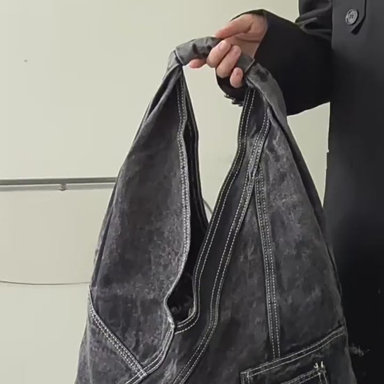 Denim triangle shoulder bag in black and light blue, shown worn and close up