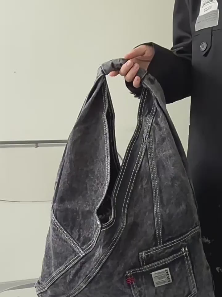 Denim triangle shoulder bag in black and light blue, shown worn and close up
