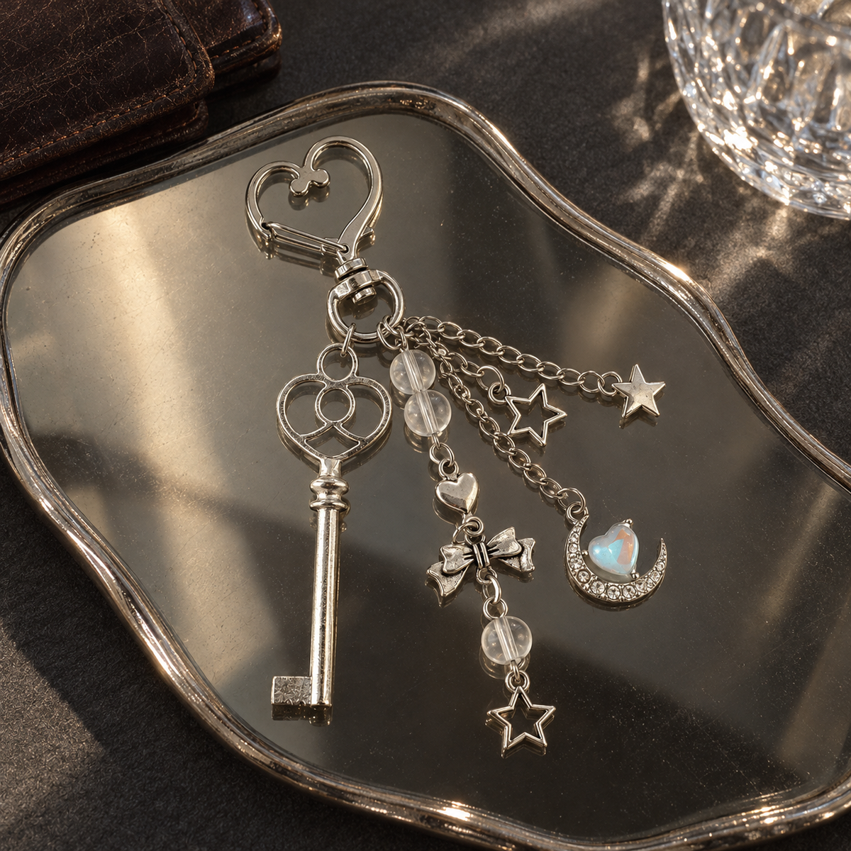 Silver key and moon charm keychain on a vintage mirrored tray